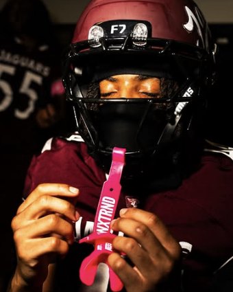 Football player in a maroon helmet with eyes closed before a game